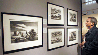 A customer looks over the selection of Thomas Hart Benton prints in the stand of The Old Print Shop.