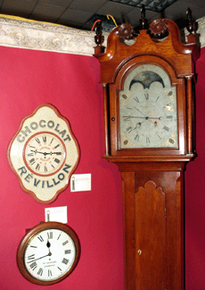Christian Eby of Manheim, Penn., tall case clock, $25,000, and a French "Chocolat Revillon” advertising clock, circa 1910-20, $2,400. Lotz's Antiques, St Louis, Mo.