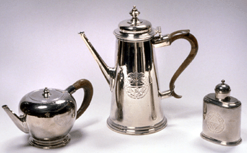 This English teapot by Peter Archambo is silver with a fruitwood handle and marked PA under a crown in a shaped cartouche with London hallmarks for 1730. One side is engraved with arms. Gift of Guy Tilghman Hollyday, Louise Este Hollyday II, Este Fisher Hollyday and Sally Levering.