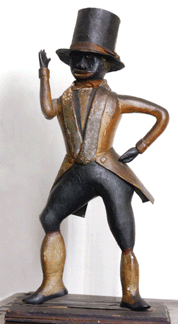 A rare and unusual carved and painted pine figure of a black man, probably New England, early Nineteenth Century, 10 inches high, dressed in tails and top hat made of tin. A high estimate of $60,000 was easily passed, with the figure selling for $90,000.