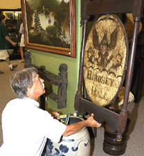 New Jersey dealer James Grievo looks over this Birdsey Hall tavern sign from Goshen Conn circa 1810 but it sold to Olde Hope Antiques for 68500