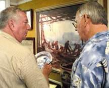 Auctioneer Bob Eldred right looks over a lot with a customer