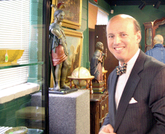 Auctioneer Michael B Grogan just before the sale stands before a cabinet filled with Peking glass