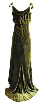 This green velvet evening dress is from the early 1930s The boat neckline sets off broad shoulders while the bias cut dress clings and swirls around the body It is accompanied with a matching jacket not shown featuring the same covered ball buttons and long sleeves It bears a McAvoy of Chicago label