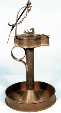 Betty lamp on tin stand. The lamp is engraved "Nancy Musser/Made By Me/John Long/Sporting/Hill 1846.” Height of lamp 5 1/8 inches, stand 7 7/8 inches. Collection of Kevin Kruger.