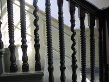 The solid cherry stair rails in the entrance hallway of the Deane House mimic a design element of the newel post in the Webb House