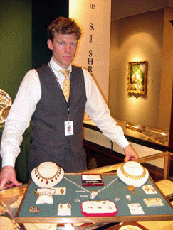 Timothy Martin of S.J. Shrubsole, New York City, displays a tray of antique jewelry, including, upper right, a Nineteenth Century Etruscan Revival parure by Robert Phillips (1810‱880) of Cockspur Street, London, influenced by Castellani, $50,000. The unsigned necklace with foil-backed cabochon garnets at upper left was $22,000.