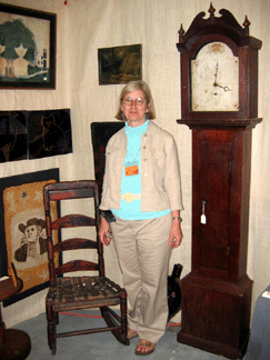 Americana dealer Judi Stellmach, Stafford Springs, Conn., loves wearing sandals in February. The tall case clock by Connecticut maker Riley Whiting has country form with little turned wooden finials and was priced at $2,450; the interesting rocking chair with make-do additions was only $250.