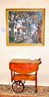 A Provincetown street scene by Philadelphia Ten artist Nancy Maybin Ferguson, which she showed in the 1934 Philadelphia Ten art show, was a big draw at the Bradford Trust booth. It  hung above an early Twentieth Century tiger maple tea cart.