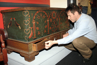 Pennsylvania dealer Gene Rappaport inspects the dated 1803 Berks County dower chest that sold to David Wheatcroft for $561,600, an auction record. The chest retains its crisply painted blue and red parrot and tulip decoration. In November 2006, Skinner sold a Berks County "black unicorn†chest for $440,000. 