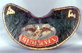 The mid-Eighteenth Century painted oil cloth parade cape belonged to a member of the Hibernia Engine Company of Philadelphia. Such capes were worn traditionally with a flat top hat, and may have inspired the long back brims of later fire hats that afforded some protection from water and embers.