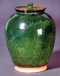 Lustrous jade-green glaze contributed to the classic appeal of this 10½-inch-tall redware jar from Bristol County, Mass. Estimated at $4/6,000, the late Eighteenth or early Nineteenth Century vessel sold by phone to David Wheatcroft for $29,375. "I've seen about ten of these in this color. Many do not have their lids or the lids are cracked,†the Massachusetts dealer said of the near-perfect piece.