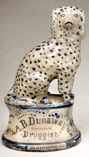 Advertising pieces, such as this elaborately decorated spaniel seated on an elevated base, proclaim the diverse variety of wares offered by the enterprise, ranging from "Seagars and Tabaco†to "Paint and Fancy Goods.†Collection of Frank, Susan and Kaitlin Swala.