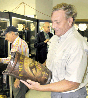 Illinois dealer Mike Whittemore inspects one of a pair of McIntire family fire buckets from Salem, Mass. The dated 1833 buckets once belonged to H.R. du Pont's sister Louise Crowninshield. They went to the phone for $52,200.