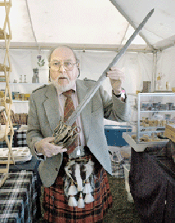 In full kilt and kit, Sir Alasdair T. Munro of Alba Antiques, Waitsfield, Vt., takes up a basket hilt officer's sword, 1796, engraved with the crown of George III.