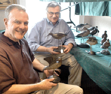 Jim Cullen, left, assisted Ron Bourgeault with the cataloging of the Crowell decorative carvings. The preening Wilson snipe held by Cullen sold at $38,280, the willet held by Bourgeault brought $92,800.