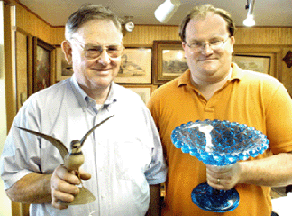 Bob and Josh Eldred with a couple of the top lots of the auction, a life-sized semipalmated plover decorative carving by Elmer Crowell that sold for $51,750, and the Sandwich glass compote that realized $28,750.