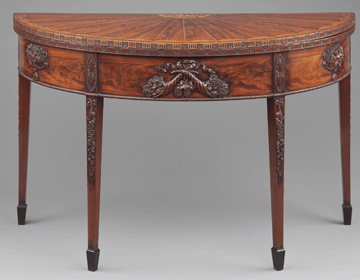 The mahogany card table is alive with McIntire's finest carved elements. It is beautifully veneered and has the square tapered legs characteristic of Salem pieces.
