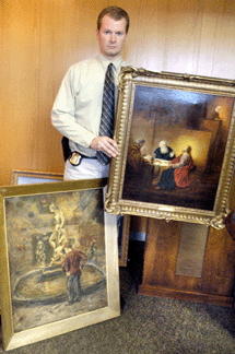Sergeant Duane Tedesco of the Waterbury Police Department with two of the allegedly stolen paintings that were discovered in the home of Diane Catalani. 
