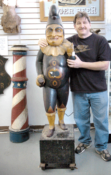 Auctioneer Philip Weiss stands with the top lot of the sale, a rare, turn-of-the-century Punch cigar store figure attributed to Samuel Anderson Robb (1851‱928). It sold for $542,400.