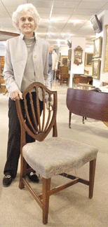 Skinner Americana expert Martha Hamilton with a Samuel McIntire-attributed Federal mahogany carved shield back chair, Salem, Mass., circa 1791. Featuring a carved basket of fruit and trailing vines carved on the upper crest rail, the chair was cataloged as "stylistically the same†as a McIntire chair in the collection of the Peabody Essex Museum, where the exhibition "Samuel McIntire, Carving an American Style†is currently on view. 