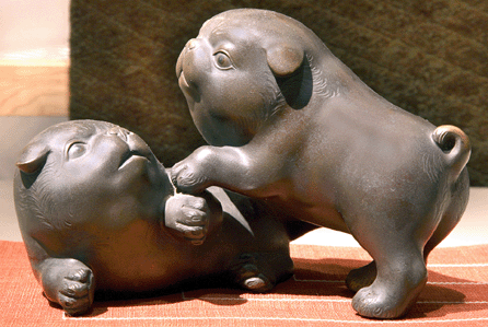 Tokumitsu (active Meiji period), bronze sculpture in the form of a pair of playing shiba dogs, Nineteenth Century, bronze, shakudô and shibuichi, 4 7/8 by 8¼ by 5¾ inches, signed Tokumitsu.