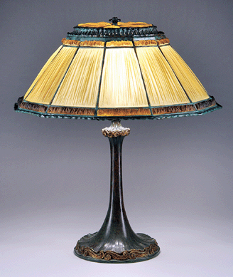 A linenfold table lamp with dark and light amber panels atop a flared base and including its original linenfold cap exceeded its estimate of $20/25,000 to bring $36,800.