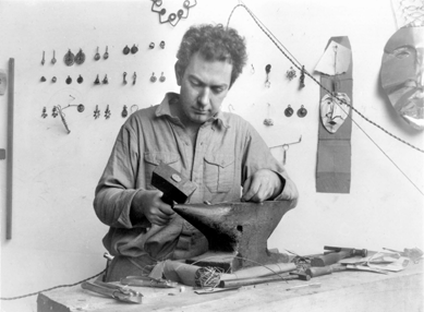 This 1930 photograph shows Calder in his Paris studio with an early nickel silver necklace on the wall. The piece's spiral form, a recurring, ancient motif, helped inject a note of primitivism into such jewelry. Therese Bonney. ©The Bancroft Library, University of California, Berkeley, courtesy Calder Foundation, New York City, 2008.