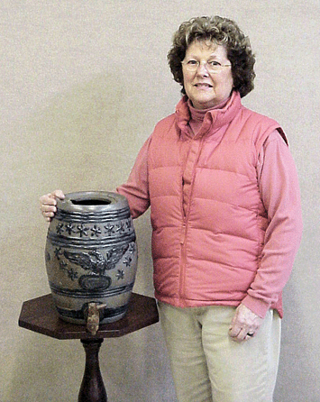 Shown here with auction gallery co-owner Jackie Hesse, the stoneware cooler that was part of the Margaret (Jane) Merrick estate from Cooperstown, N.Y., sold for a record $58,300, hammered down to a phone bidder from Richmond, Va. The cooler, dating from the Nineteenth Century, had a dark blue embossed American eagle and 13 stars. It was found nearly hidden away in the Merrick home on top of a corner cupboard.