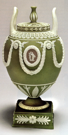 An early Twentieth Century peach green jasper covered vase with ornate decoration and unusual vertical loop handles, marked "Wedgwood,†"J†and "England.• style=