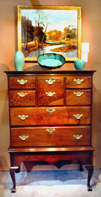 An unusual walnut Chippendale chest on frame with seven drawers and bonnet drawer on top topped with scalloped Galloway black and blue-green dishes, Philadelphia origin, at H.L. Chalfant Antiques, West Chester, Penn.