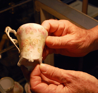Nelson Barry of Dolphin Antiques of Weymouth, Mass., demonstrates the interesting textures of a Royal Bayreuth "Rose Tapestry†teacup. ⁆rances McQueeney-Jones Mascolo photo