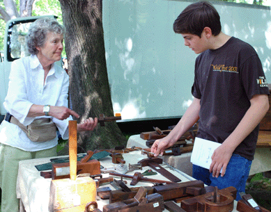Kay Baker of Amherst, Mass., was able to buy a whole collection of old tools, and she shows young collector Colin McIntire, 14, of Darien what is unique about an antique plane.