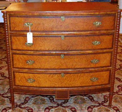 A Sheraton birch bowfront bureau with bird's-eye maple, mahogany and other veneers, a cookie corner top and a central inlaid drop brought $8,280.