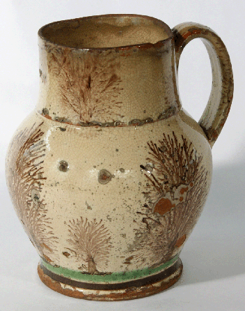 "His competitive nature is quite evident in his production of sophisticated items not normally made in the backcountry,†said Dr George Manger of John Bell. A superb example is this redware pitcher using a tin glaze that created the cream-colored body glaze that is accentuated with a "seaweed†decoration seen in the imported English mocha wares. 