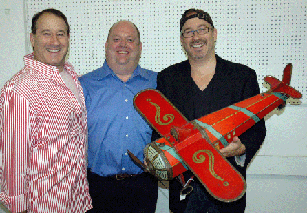 From left, Leon Weiss, Ray Haradin and Steven Weiss, principals of RSL Auction Co., prior to the sale with one of the important toys in the auction, a Belgian aeroplane biscuit tin, painted tin and in excellent condition; it sold for $3,818. The plane dates circa 1915 and measures 31 inches long with a 26-inch wingspan.