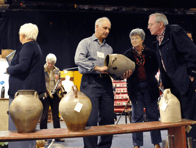 Steve German, left, shows clients one of many pieces of stoneware that he had on display.