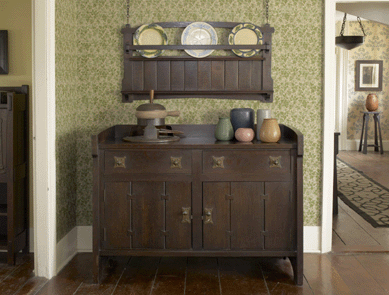 An interior view of Stephen Gray's dining room with a Gustav Stickley server decorated with butterfly tenons on the cabinet doors and a hanging plate rack. 