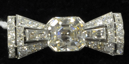 Containing 36 diamonds, including a central 6-carat, emerald-cut diamond, the gold bow-form pin sold for $28,750.