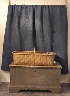 Colette Donovan, Merrimac, Mass., showed a wonderful splint basket, 43 inches long, atop an early Eighteenth Century Pennsylvania chest in poplar with a blue linsey-woolsey hanging in back.