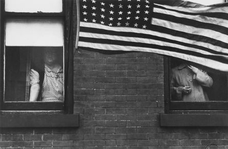 In this tight, static photograph, "Parade †Hoboken, New Jersey,†1955, Frank recorded two ordinary women in a drab building looking out at a festive scene that they can hardly see through the American flag draped in front of them. They symbolize the powerless poor, who see but cannot act. Private collection, San Francisco. ⁐hotograph ©Robert Frank, from The Americans