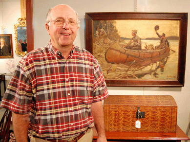 Auctioneer Charlie Cobb is shown with a previously unknown sporting painting by Phillip Russell Goodwin that brought $80,500. The early Nineteenth Century New England paint decorated dome top box below the picture realized $4,025.