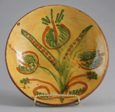 A Nineteenth Century slipware pie plate featuring a floral motif was popular with the crowd; it sold for $13,200.