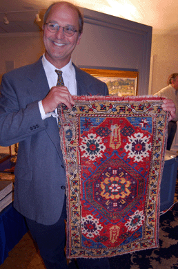 Auctioneer Michael March is pictured with the beautifully hued antique Yastik rug that measured 34 by 21 inches and realized $2,070.