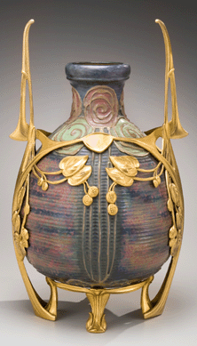 An exotic and colorful 23-inch urn with from the Bohemian pottery Riessner, Stellmacher and Kessel Amphora Pottery was made with a layered and multicolor glaze and supported by bronze mounts. The roses were made with threads of extruded clay. The vibrant colors and design offer a distinct contrast with most American art pottery.