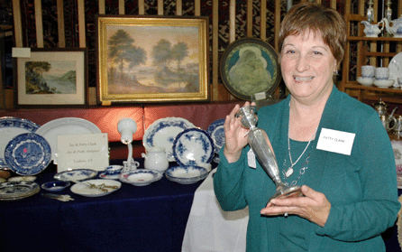 Patty Clark of Jay and Patty Antiques, Ludlow, Vt., holds one of a pair of 1920s Cowell & Hubbard candlesticks that were $625 for the pair. She had two pairs available. 