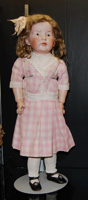 A German Kestner character girl, circa 1910, with a bisque head, a mohair wig and a painted face on a fully jointed composition body sold for $37,920. In a reflection of the times, the doll wore a pink cotton check dress and a pink ribbon in her hair.
