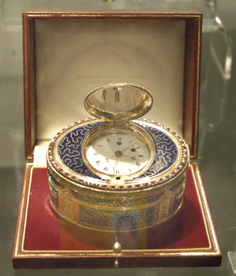 The Antique Enamel Company, London, showed a Swiss gold and enamel Cyrillic music box with a diamond skeleton split second watch in the lid, circa 1800.
