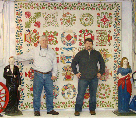 Mike and Seth Fallon are shown during the auction with the two top lots of the sale, the Baltimore album quilt and the pair of George Washington and Lady Liberty dumb stoves that brought $28,250 and $22,600, respectively. 