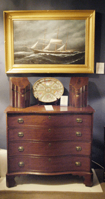 The Hanebergs, East Lyme, Conn., showed this oil on canvas of the American bark Essex, which was built in Newburyport, over a cherry serpentine front chest of drawers, circa 1790, topped with a pair of English mahogany knife boxes with fine inlay.